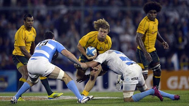 True grit ... Wallabies winger Nick Cummins runs into a tackle from Argentinian flankers Tomas Leonardi and Julio Farias Cabello in Rosario yesterday. Australia recorded a gutsy six-point win.