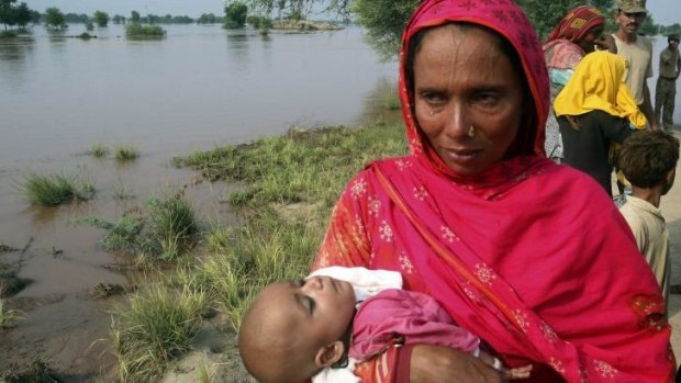 A mother carrying a child cries while evacuating her home along the flooded Chenab River, in Jhang, Pakistan.