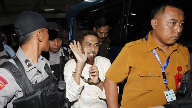 Umar Patek waves to journalists as he arrives at court in West Jakarta.