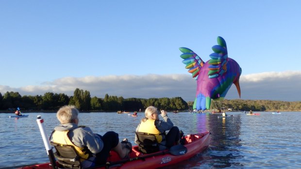 Sharon and Leeanne Chaffer in a kayak look on as the humming bird balloon skims Lake Burley Griffin.