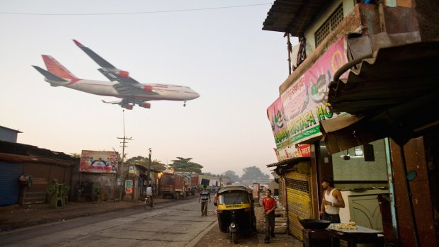 A man makes chapatis as an Air India passenger jet flies over the Jari Mari slum before landing at Mumbai Airport.