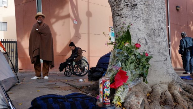 Ceola Waddell, 58, left, a homeless man who says he witnessed the police shooting on Skid Row on Sunday, stands by a street side memorial for the victim in downtown Los Angeles.