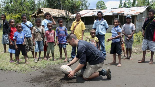Improvising: New Penrith  pivot Jamie Soward takes a break from the club's Kokoda trek to line up a shot, to the delight of these PNG village children.