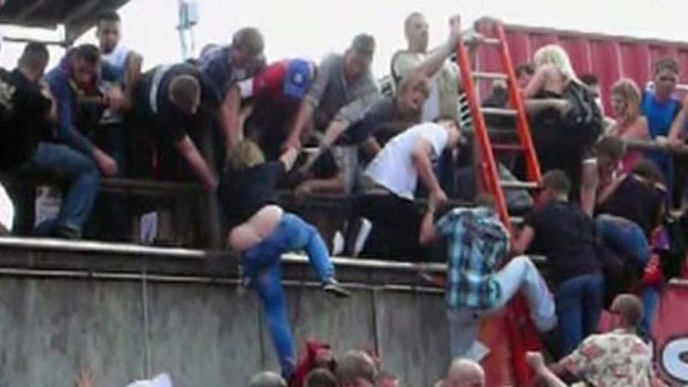 People try to escape over a wall  after a panic at Loveparade 2010 in Duisburg, Germany.