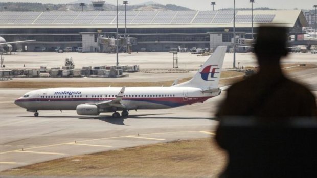 A man looks on as an aircraft operated by Malaysian Airline taxis on the tarmac at Kuala Lumpur International Airport.