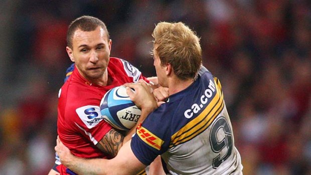 Reds' five-eighth Quade Cooper finds his way blocked by Brumbies' scrum-half Luke Burgess.