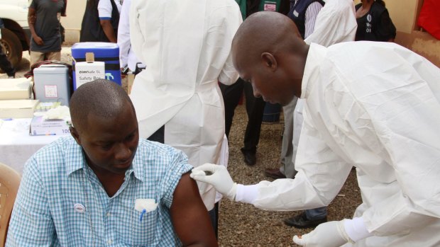 A health worker, right, cleans a man's arm before injecting him with a Ebola vaccine in Conakry, Guinea. The trial of the VSV-ZEBOV vaccine has been 100 per cent effective, according to WHO.