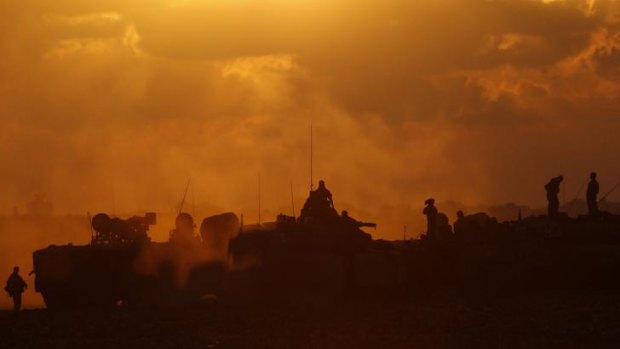 Israeli soldiers stand on top of their tanks across from the northern Gaza Strip.