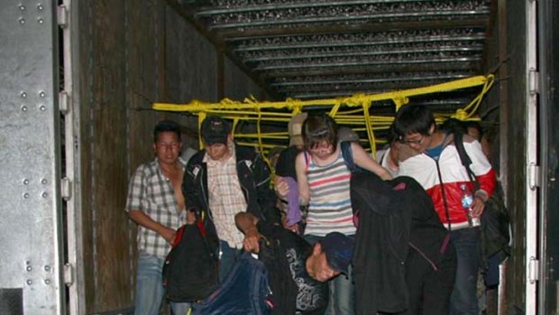 Caught ... immigrants climb out of one of the trucks.