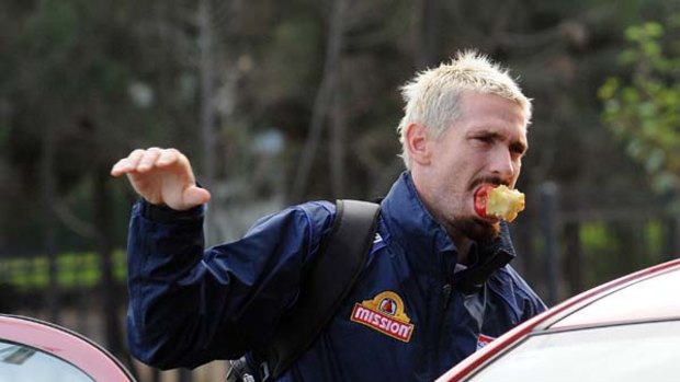 Jason Akermanis bites off something he can chew - an apple - as he arrives at the Whitten Oval for training yesterday.