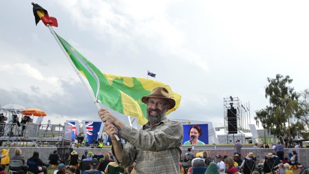 Ian Robertson of Morisset waves the Aboriginal and a Green and Gold flag.  