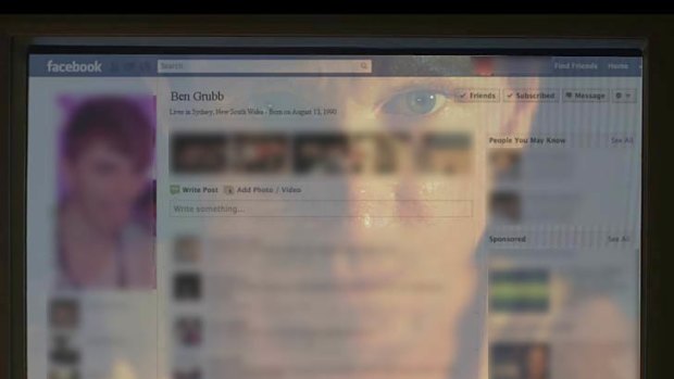 The man's reflection is seen on a computer monitor as he looks through your Facebook profile.