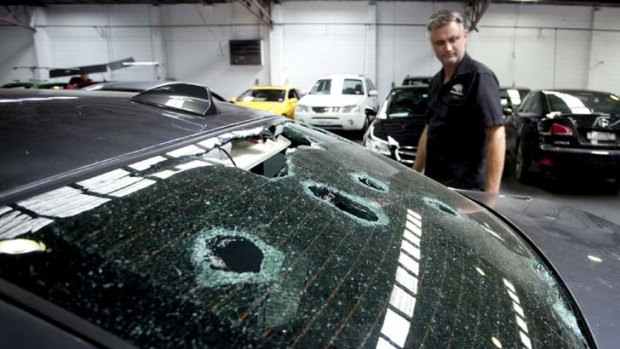 Australasian Hail Network  director Adam Woodlands inspects a car damaged in the Christmas day storm.