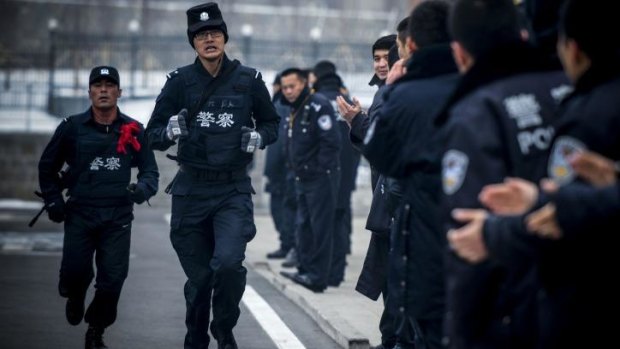 Two SWAT policemen  running while taking part in a competition during their winter training session in Urumqi, in China's restive Xinjiang region.