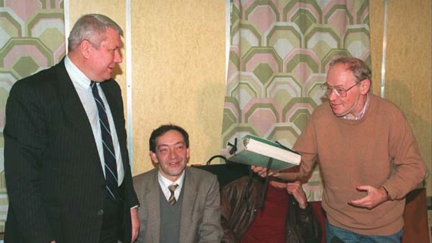 In this October 17, 1995 file photo, former dissident Alexander Ginzburg, 59, right, holds a folder, containing selected documents from Ginzburg's KGB files given to him by Federal Security Service (FSB) archive's head Vladimir Vinogradov, in Moscow.