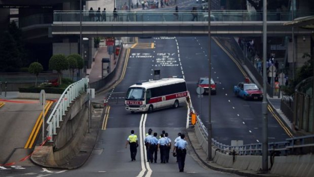 Police officers leave an area as protesters block the surroundings of the government headquarters building in Hong Kong.