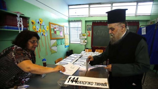 More than one nation's fate in his hands ... a Greek Orthodox priest casts his vote in an Athens primary school yesterday.