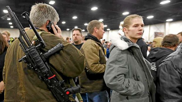 A man talks on a mobile phone while carrying a semi-automatic assault rifle he is trying to sell at the 2013 Rocky Mountain Gun Show in Utah.