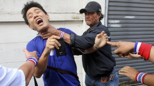 Anti-government protesters attack a voter near a polling station in Bangkok earlier this year.