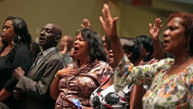 Mourners attending the funeral service for Michael Brown sing to celebrate the life of the teenager in St Louis.
