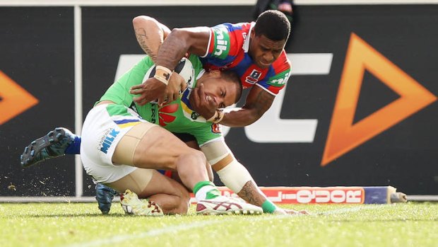 Kevin Naiqama of the Knights attempts to pull Blake Ferguson of the Raiders over the try line.
