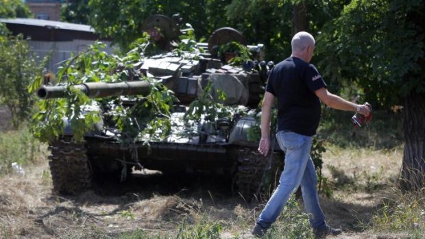 A local resident passes by a camouflaged pro-Russian tank in the town of Novoazovsk, in eastern Ukraine.