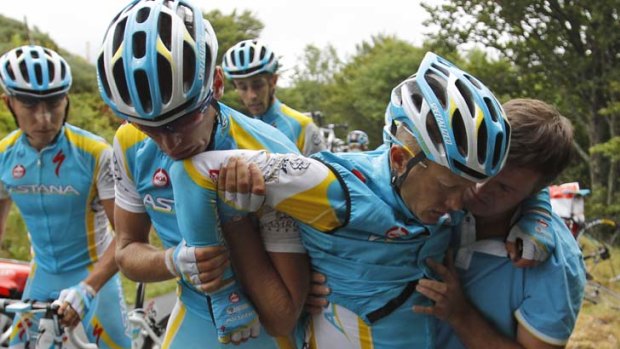 Alexande Vinokourov of Kazakhstan, second right, is helped by his teammates after crashing during the 9th stage of the Tour de France.