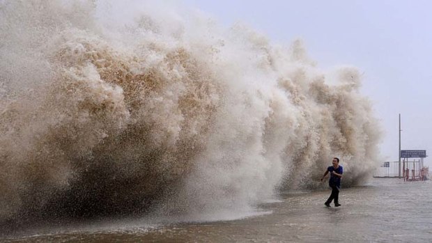 A man stands in front of a wall of water thrown up by Typhoon Wutip.
