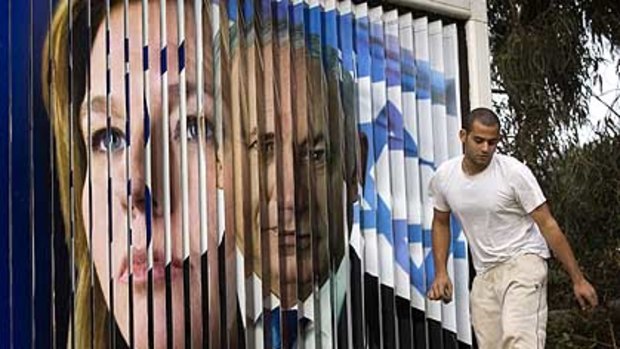 Changing faces: A worker passes a rotating sign showing Israeli Foreign Minister and Kadima Party leader Tzipi Livni, left, and Likud Party leader Benjamin Netanyahu in Tel Aviv, Israel.