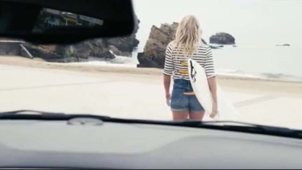 The woman then gets in a car before arriving at the beach with her surfboard.