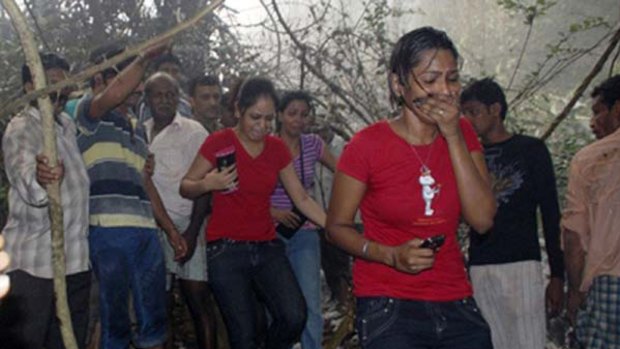 Local residents react after seeing the site of a plane crash in Mangalore.