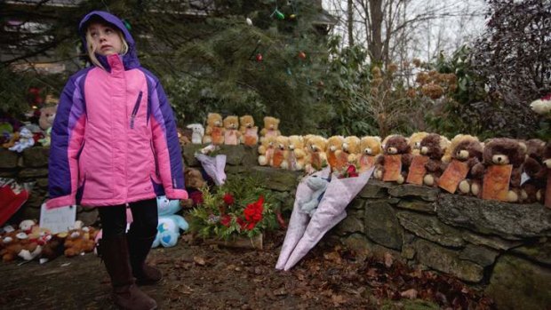 Ava Staiti, 7, of New Milford, Connecticut., looks up at her mother while visiting a sidewalk memorial with 26 teddy bears, each representing a victim of the Sandy Hook Elementary School shooting.