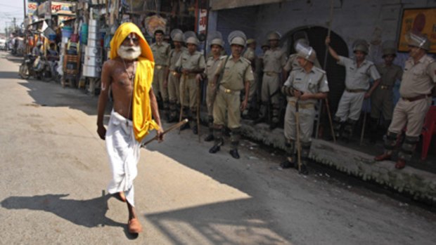 A Hindu holyman walks past  security forces  standing guard in Ayodhya, India, anticipating  communal tensions will flare up in reaction to an imminent court ruling.
