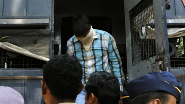 One of the men convicted of gang raping a photojournalist exits a police van as he is brought to prison.