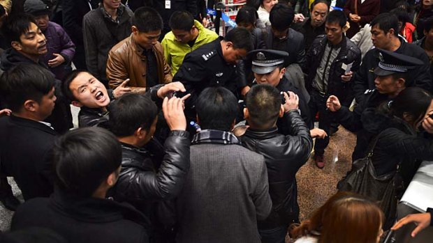 Stranded travellers argue with police and airline staff at Changshui International Airport.