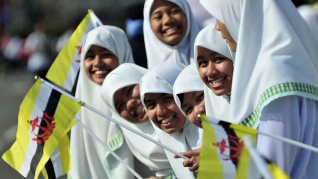 Rich colour: Bruneians wave the national flag.