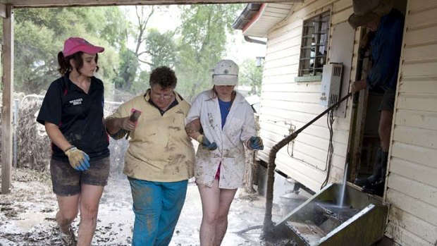 Trying time &#8230; volunteers help Patricia Budd as she returns to her home in Mitchell, about 500 kilometres west of Brisbane, to survey flood damage.