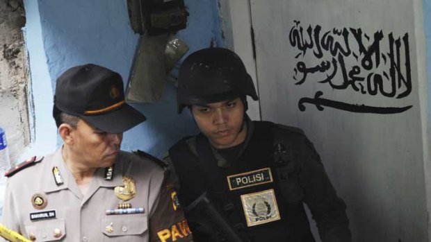 An official from the Special Detachment 88 squad and a police officer stand guard outside the house of a suspected militant after a raid in Jakarta.