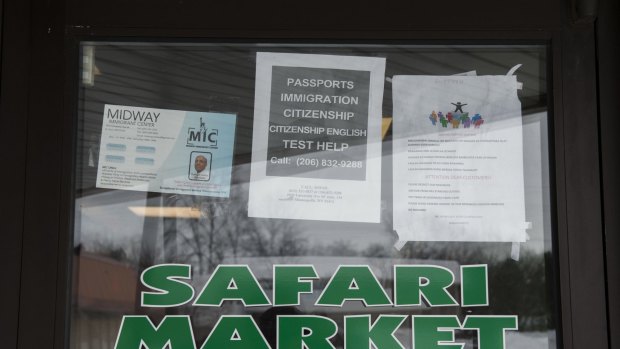 Signs on the door of Safari Market, a Somali-owned coffee shop and grocer that caters to the local Muslim community, advertise services for immigrants. 