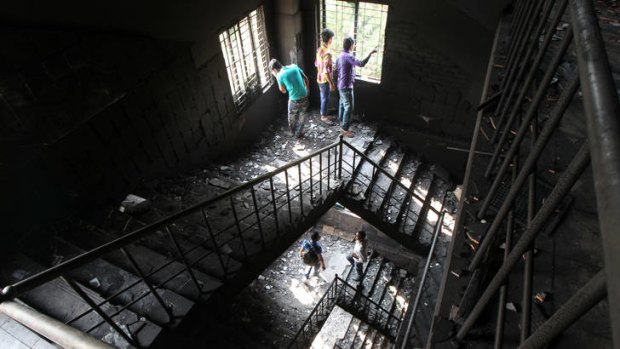 Grim scenes ... Bangladeshi garment workers inspect the Tazreen Fashion factory where more than 100 of their colleagues died.