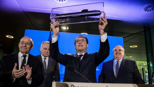 French President Francois Hollande, center, shows off a model of a submarine.