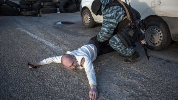 A Pro-Russian serviceman searches a man at Chongar checkpoint blocking the entrance to Crimea.