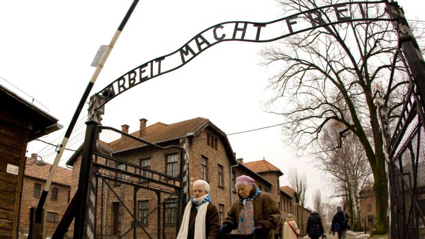Concentration camp survivors walk out of the Auschwitz Museum's main gate near Auschwitz-Birkenau, in 2009. The sign 'Arbeit macht frei' means 'Work will make you free.'