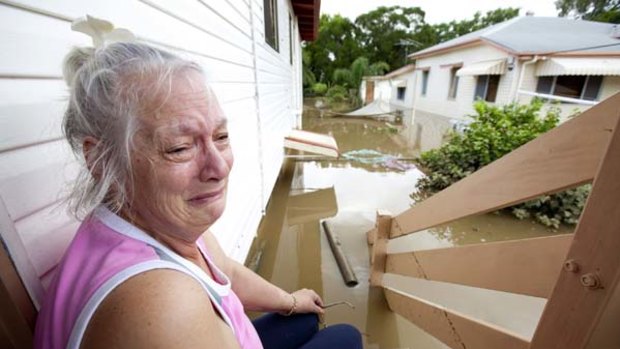 Anne Smart sits on the steps of her flooded house in Ipswich.