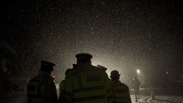 Police officers wait in heavy snow  outside Ellingham Hall, the bail address of WikiLeaks founder Julian Assange.