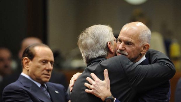 Deserted ... Silvio Berlusconi looks on as the leaders of Greece and Luxembourg, George Papandreou and Jean-Claude Juncker, embrace at the European Council last month.