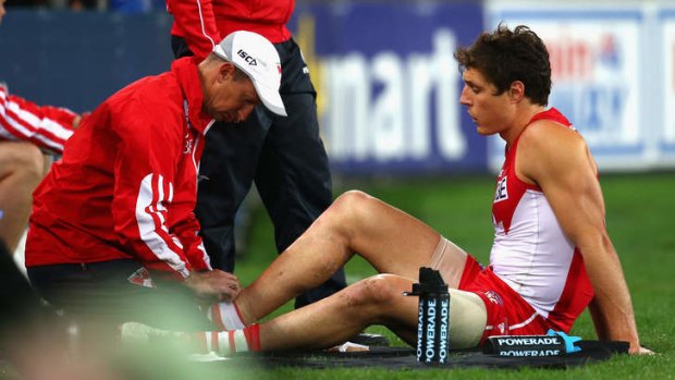 Ligament damage: Kurt Tippett is treated for a leg injury during the Swans' game against Carlton on Saturday night.