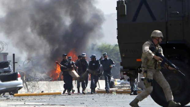 Afghan policemen carry a casualty from the blast site.