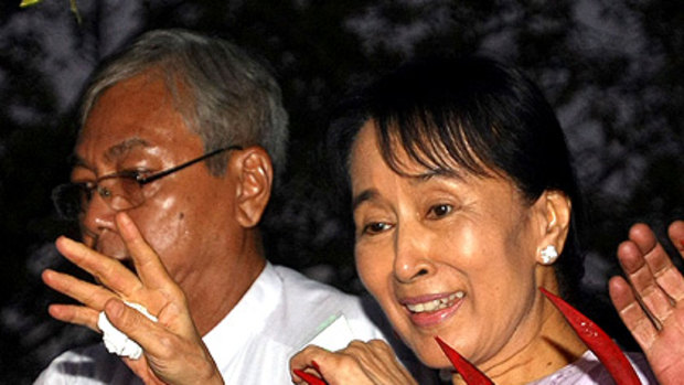 Aung San Suu Kyi waves to a crowd of supporters gathered outside her house following her release.