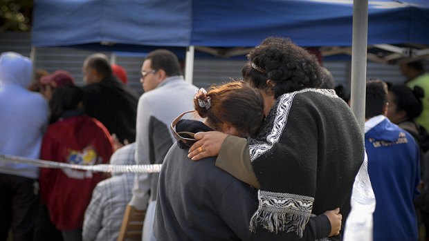 Family and friends of the eleven people believed to have died in the fire gather at the scene.